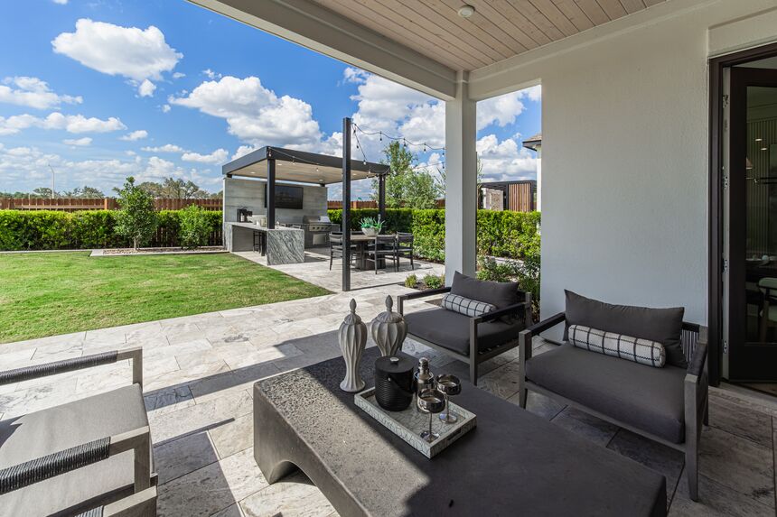Covered patio with lounge chairs and a view of the backyard lawn