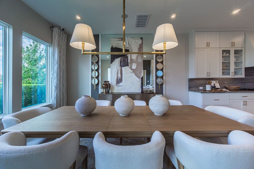 Dining room with a long wood table and white upholstered chairs
