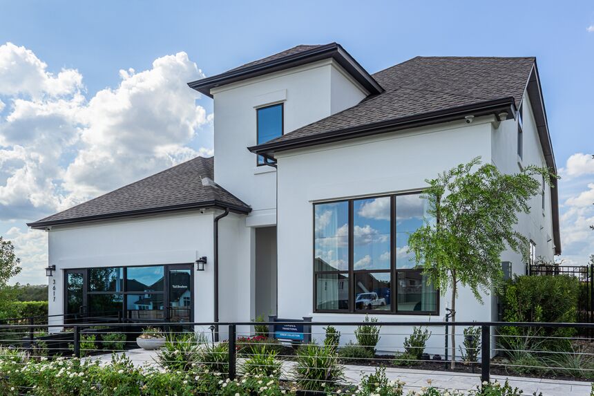 White two-story home with dark roof and a black metal fence