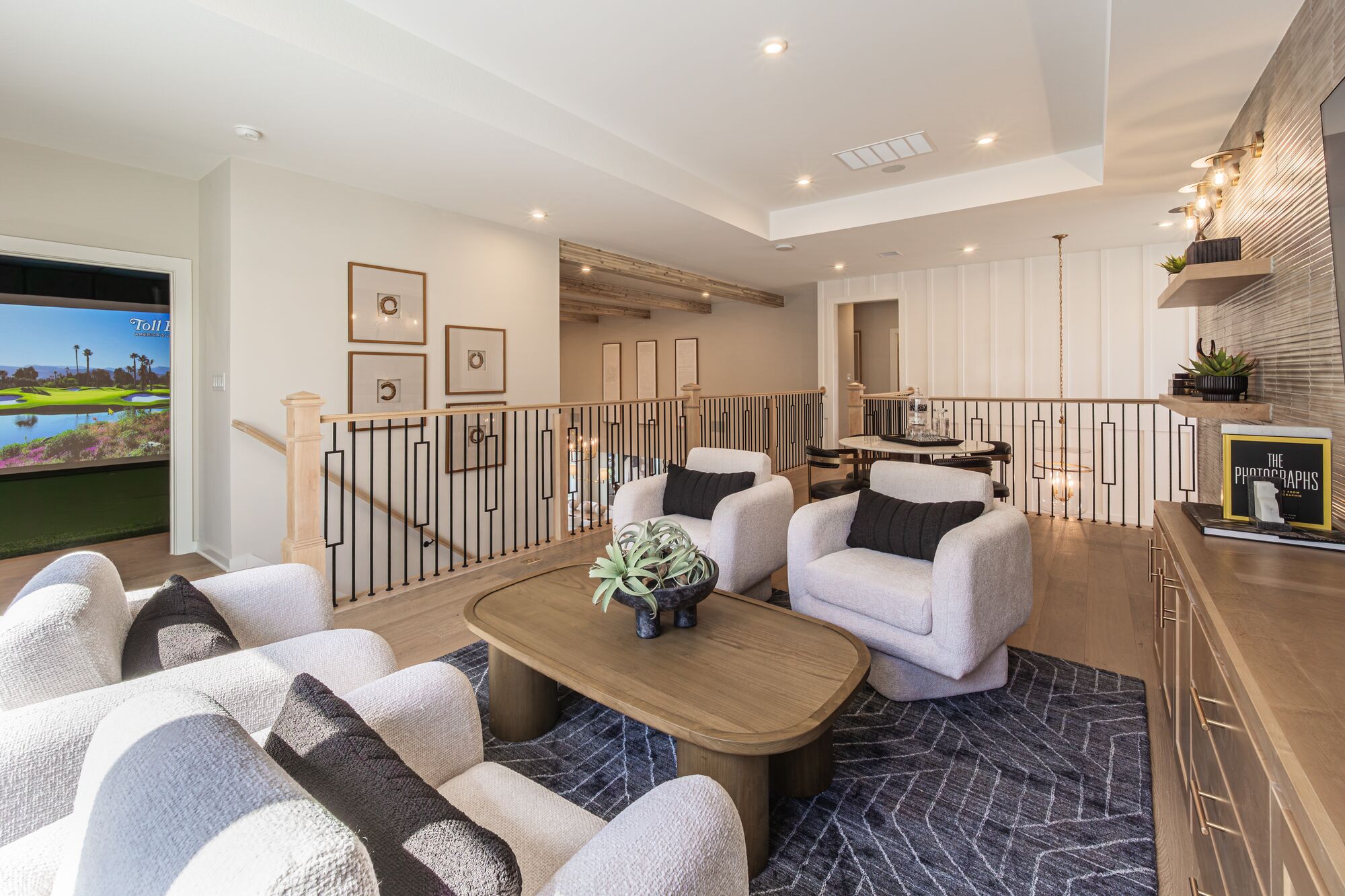 Game room with lounge chairs and a golf simulator in a Leander model home