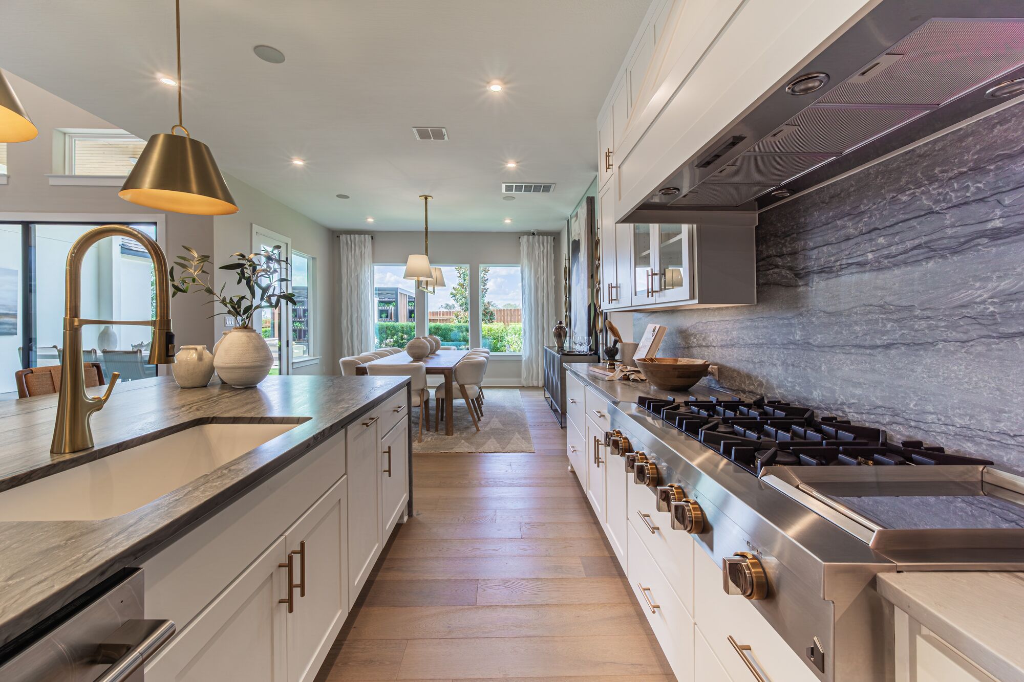 Kitchen with brass pendant lights and windows to the backyard in a Leander model home