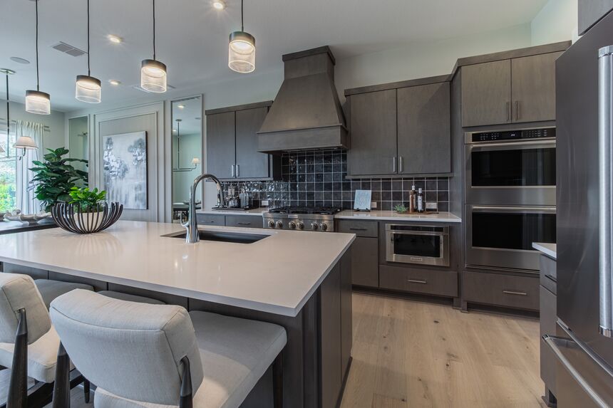 Kitchen with dark cabinets, a range hood and a white quartz island
