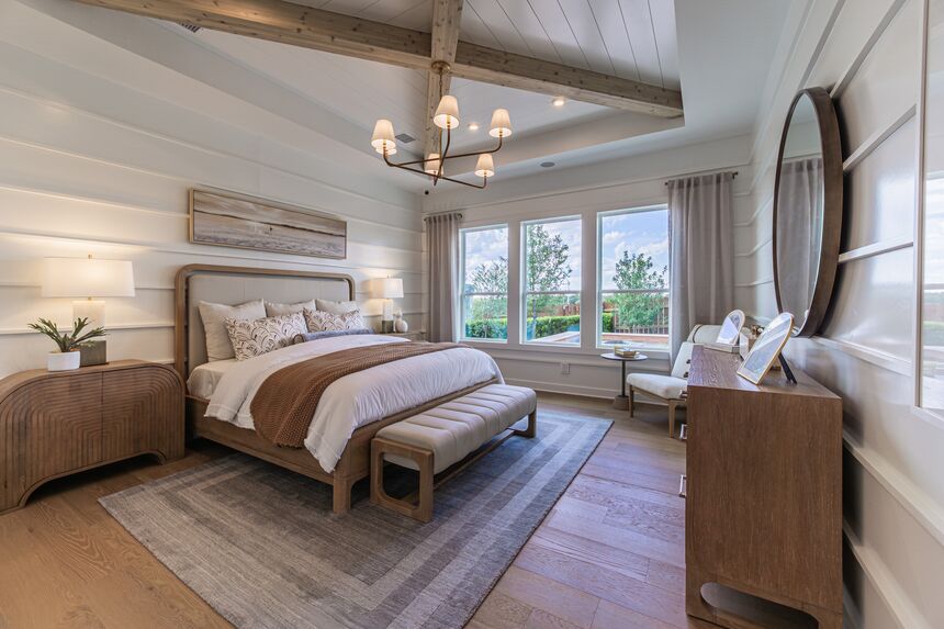 Primary bedroom with a wood beam ceiling and a bench at the foot of the bed